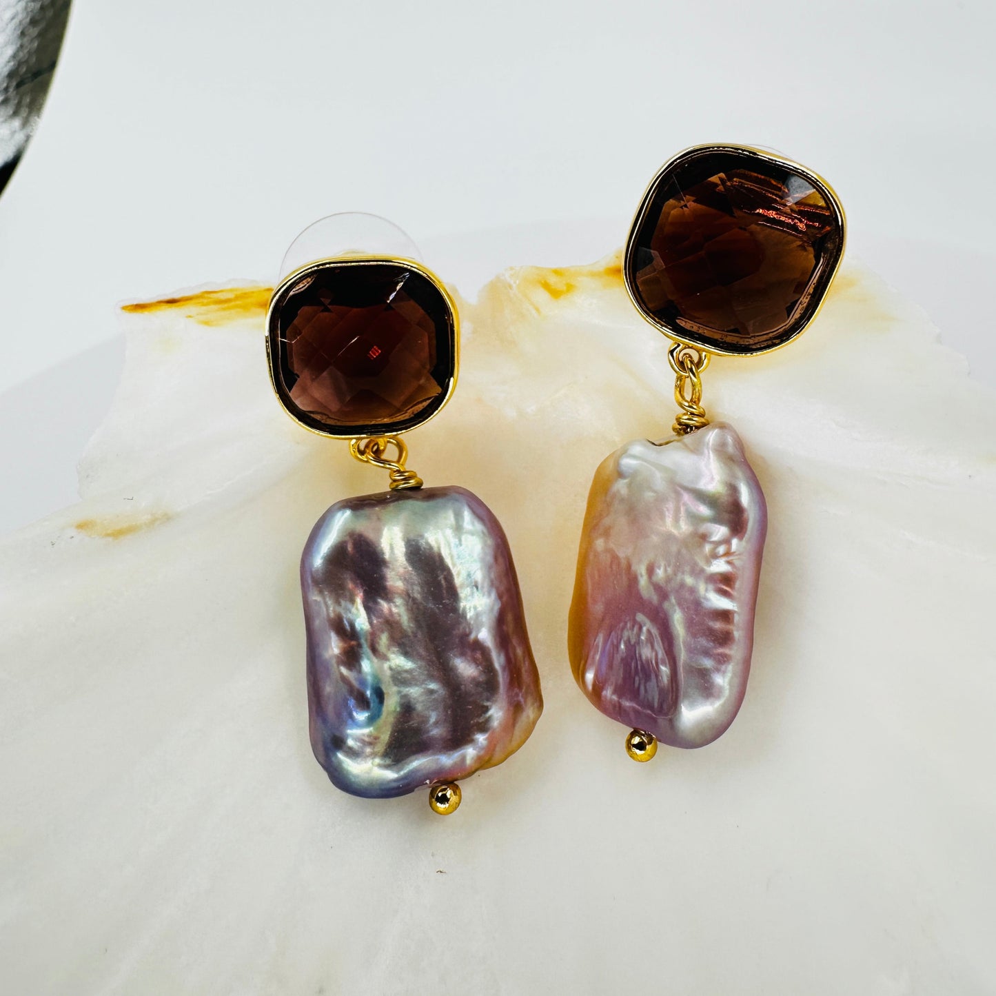 Close-up of faceted purple zirconia and iridescent baroque pearl