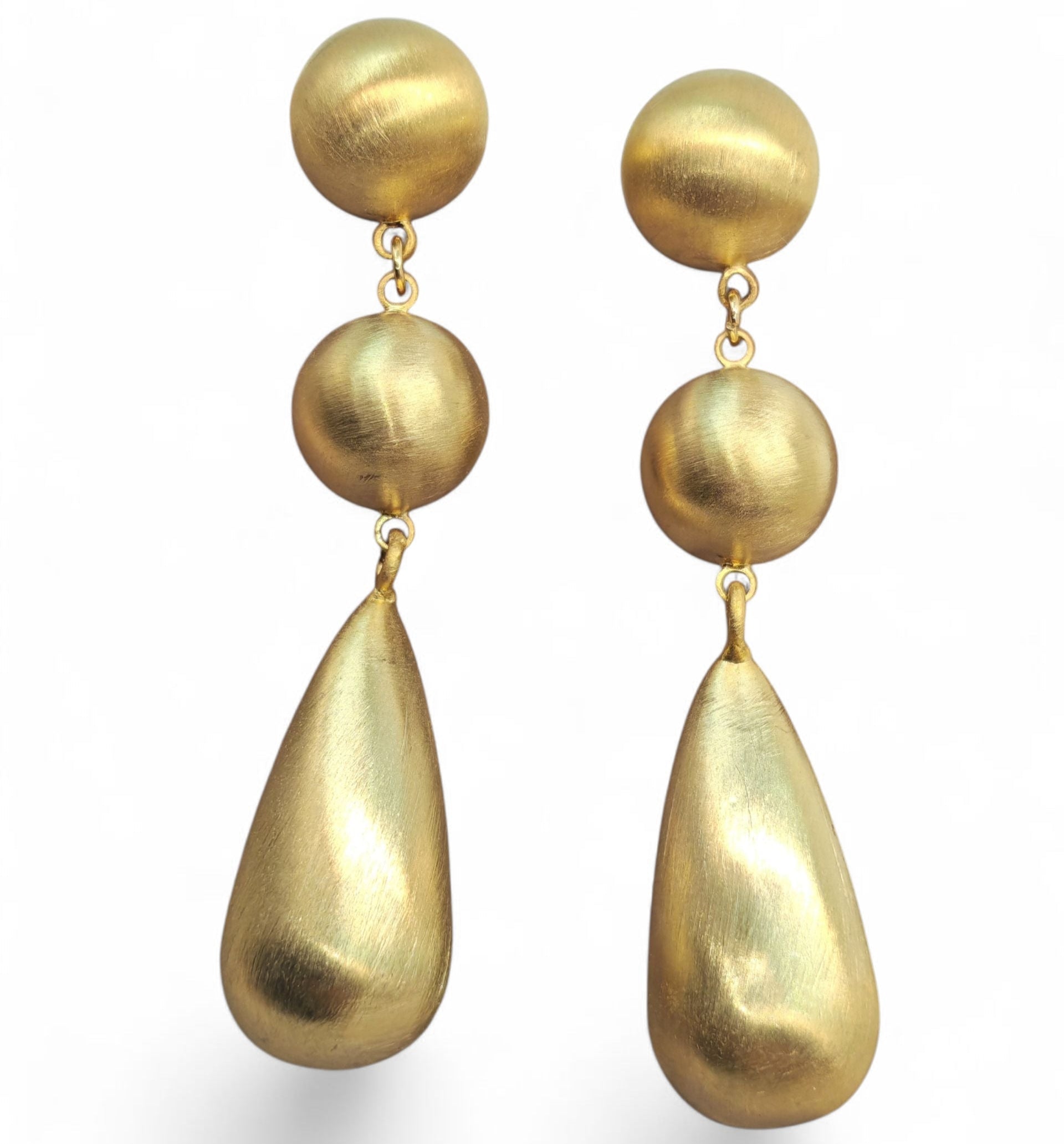 Pair of gold earrings with spherical and teardrop shapes on a white background