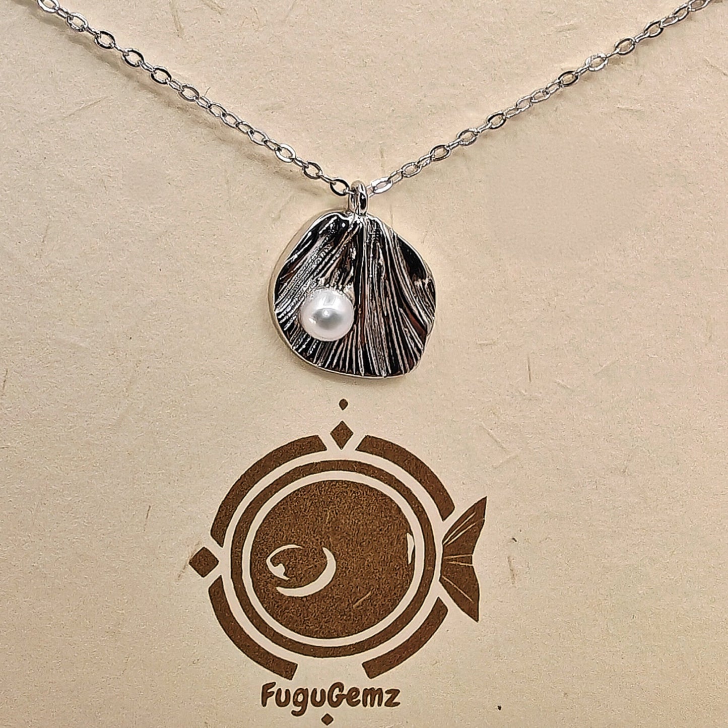 Close-up of textured silver leaf and pearl with Fugugemz branding