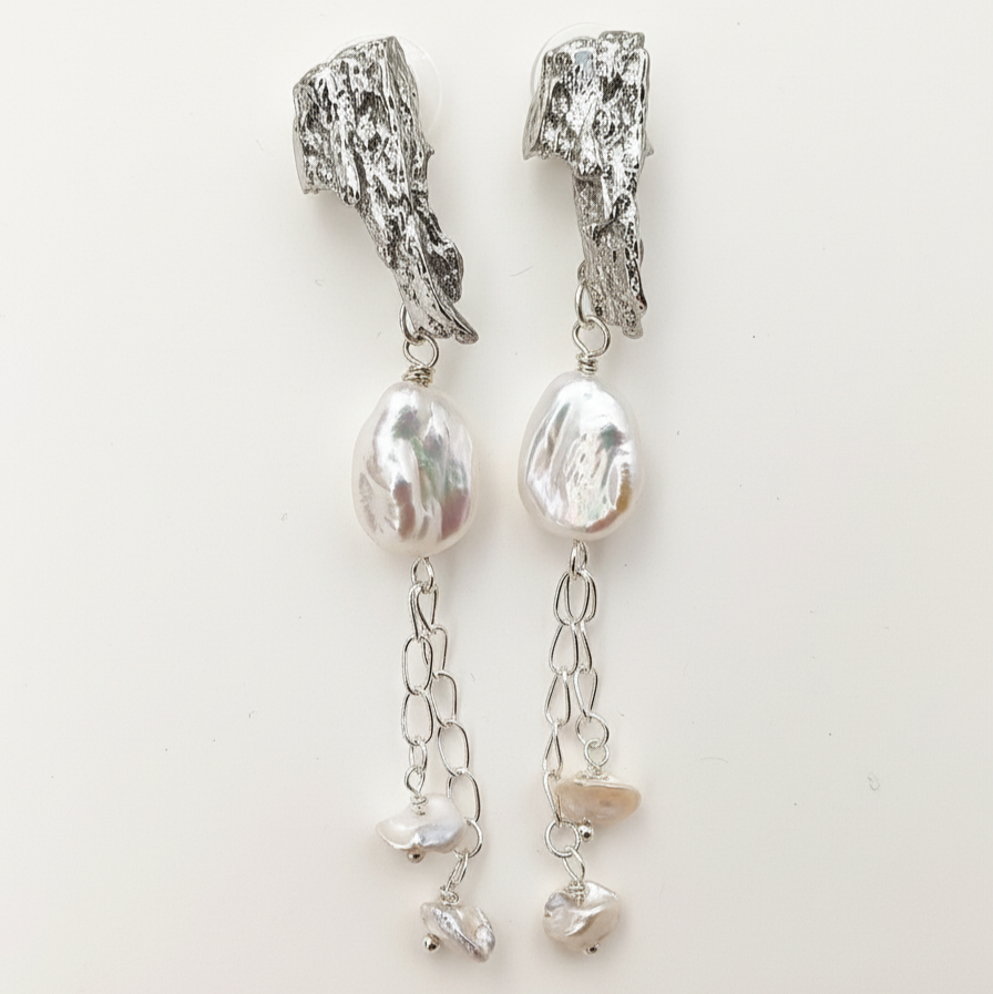 Woman wearing platinum and pearl earrings on ears