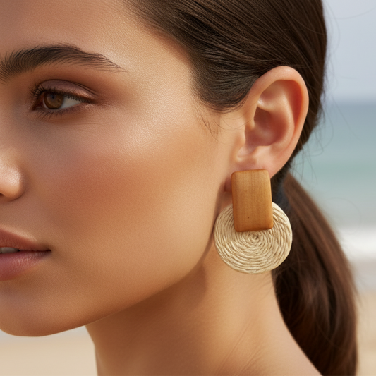 Close-up of a woman wearing gold hoop earrings with a blurred beach background