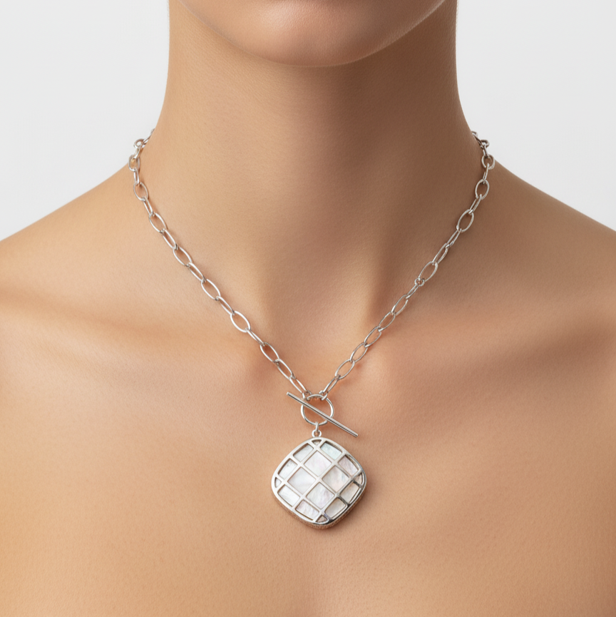 Silver necklace with a checkered pendant worn by a model on a neutral background
