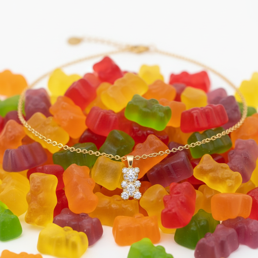 Gold necklace with a diamond pendant surrounded by colorful gummy bears on a white background