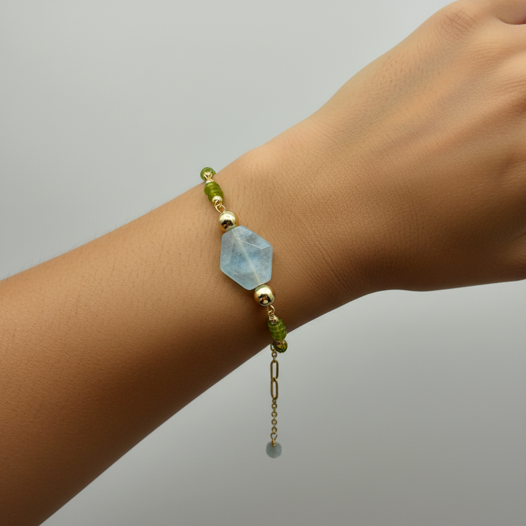 Bracelet with green and gold beads on a wrist against a gray background