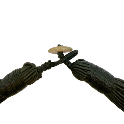 Close-up of a black tassel with a wooden ring on a white background
