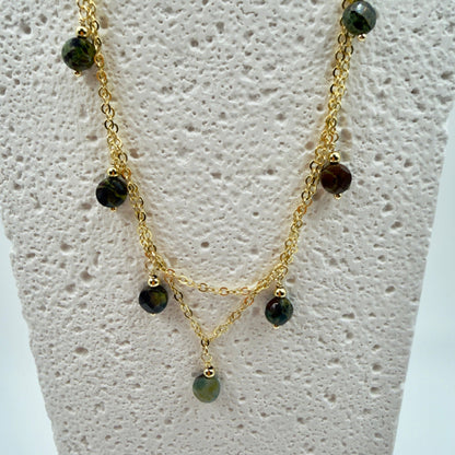 Gold necklace with green beads on a mannequin