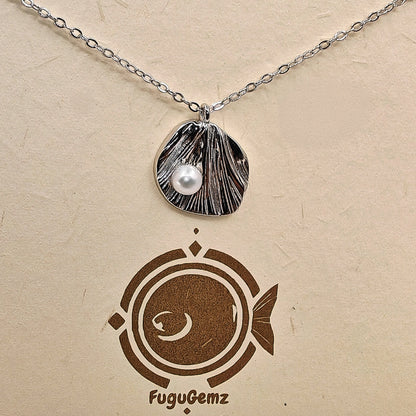 Close-up of textured silver leaf and pearl with Fugugemz branding