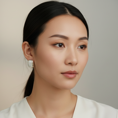 Woman wearing square mother-of-pearl stud earrings with natural makeup and loose hair