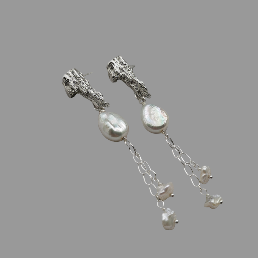 Woman wearing platinum and pearl earrings on ears
