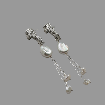 Woman wearing platinum and pearl earrings on ears
