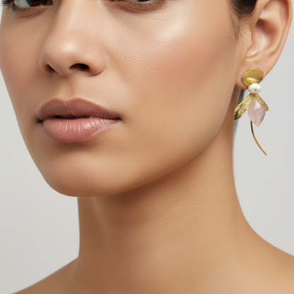 Woman wearing gold-plated leaf earrings with rose quartz and pearl