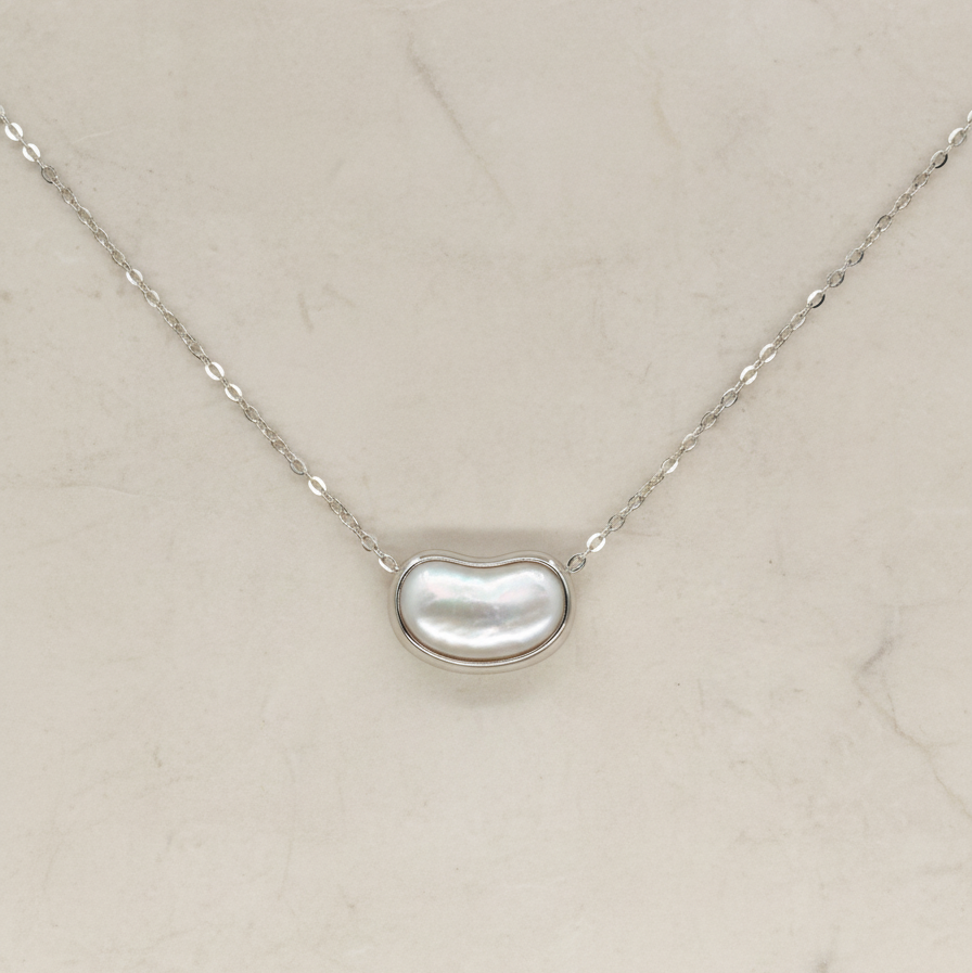 Necklace with a kidney-shaped pearl pendant on a light beige background