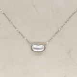 Necklace with a kidney-shaped pearl pendant on a light beige background