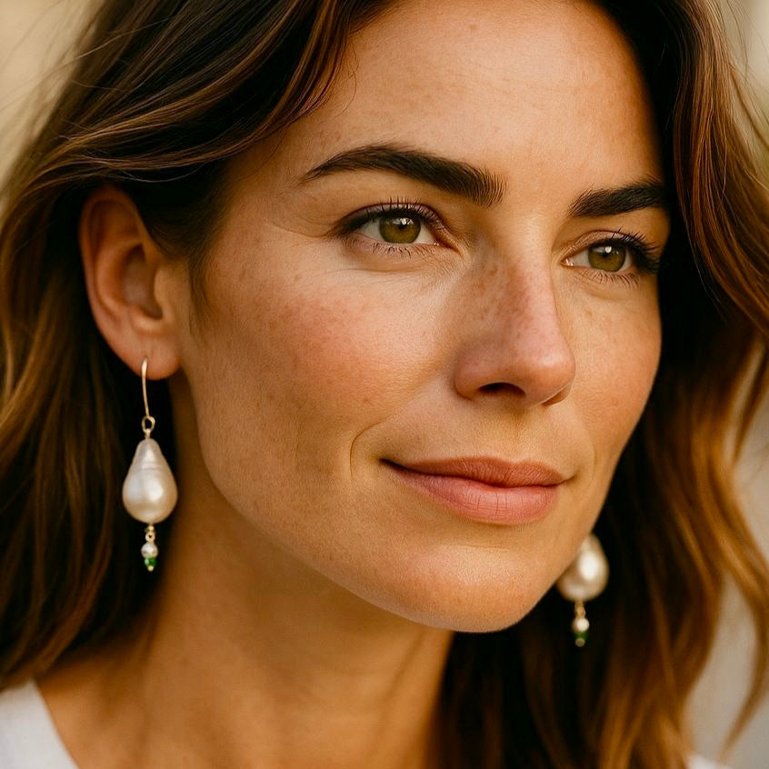 Woman wearing long baroque pearl and turquoise earrings with soft waves