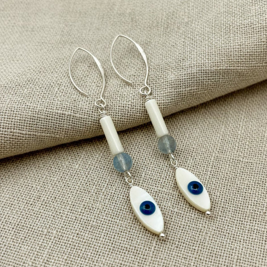 A pair of extra-long 76mm dangle earrings featuring a mother of pearl evil eye and an aquamarine bead.