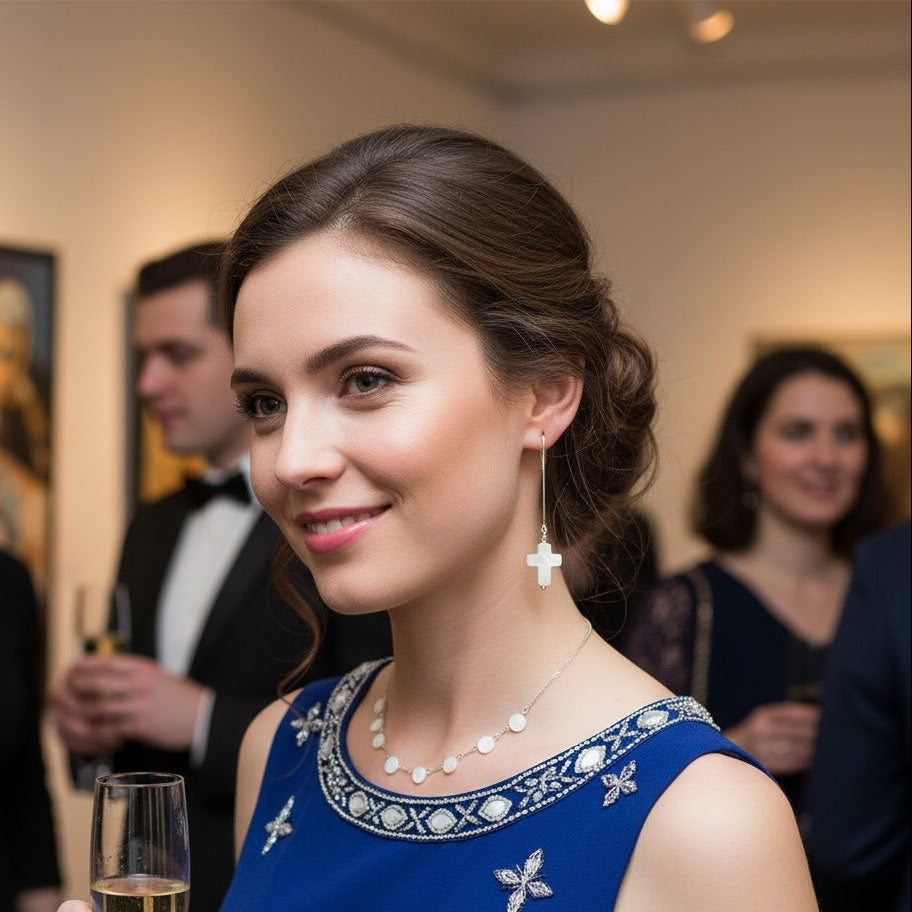 Woman wearing silver threader earrings with pearl cross