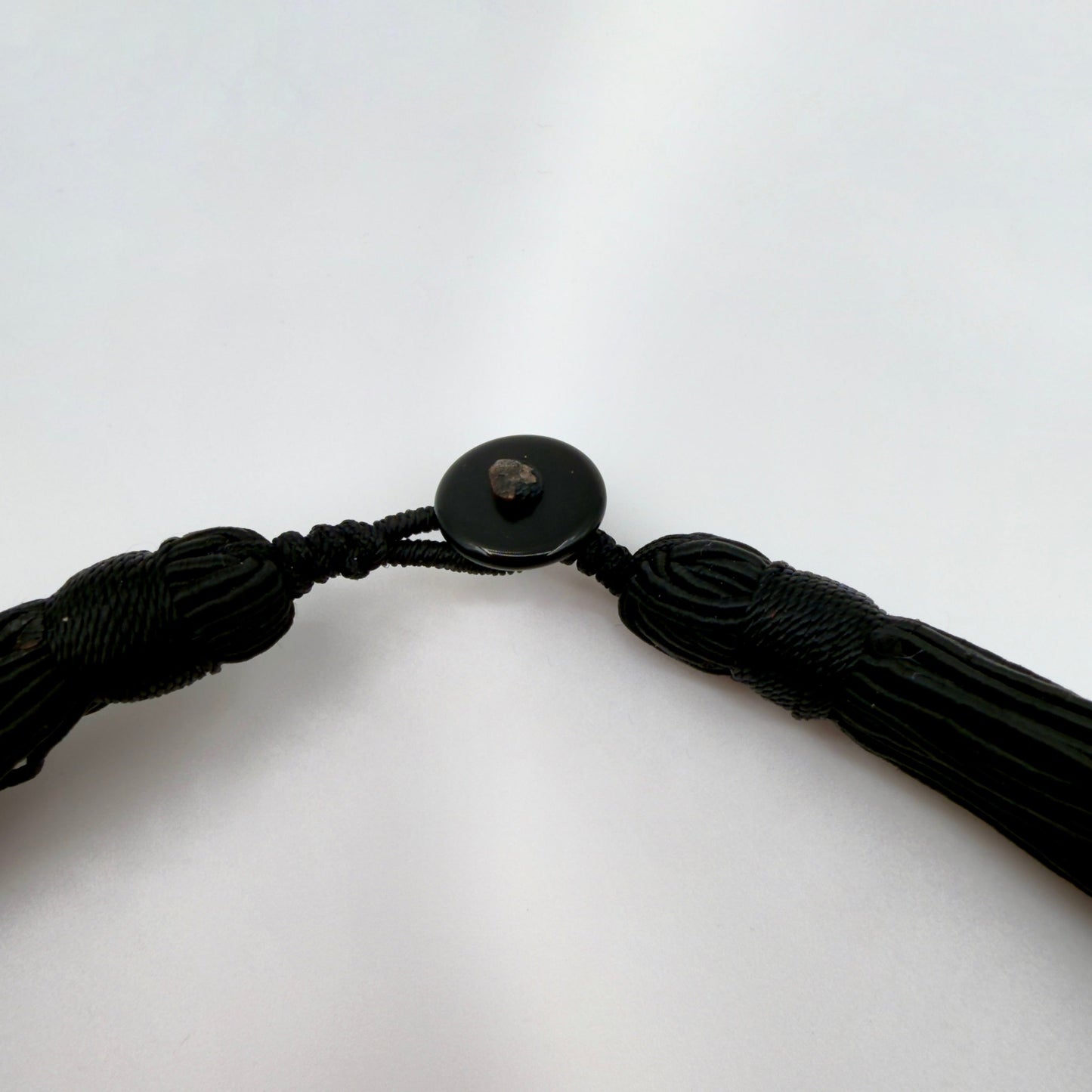 Black braided cord with a button on a white background