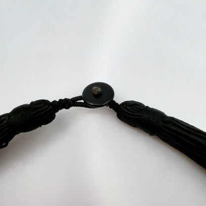 Black braided cord with a button on a white background