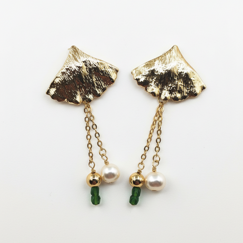 Gold leaf-shaped earrings with green beads and pearls on a white background